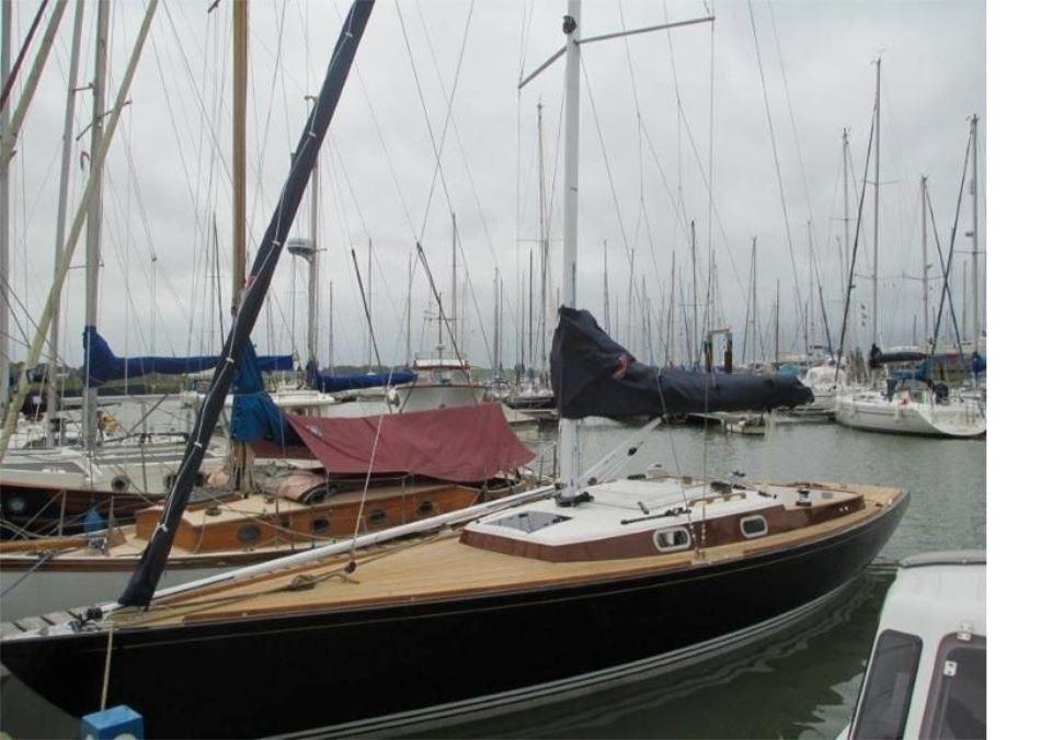 Sailboat in marina, Rustler 33 model, 2025, with wooden deck and covered sails.