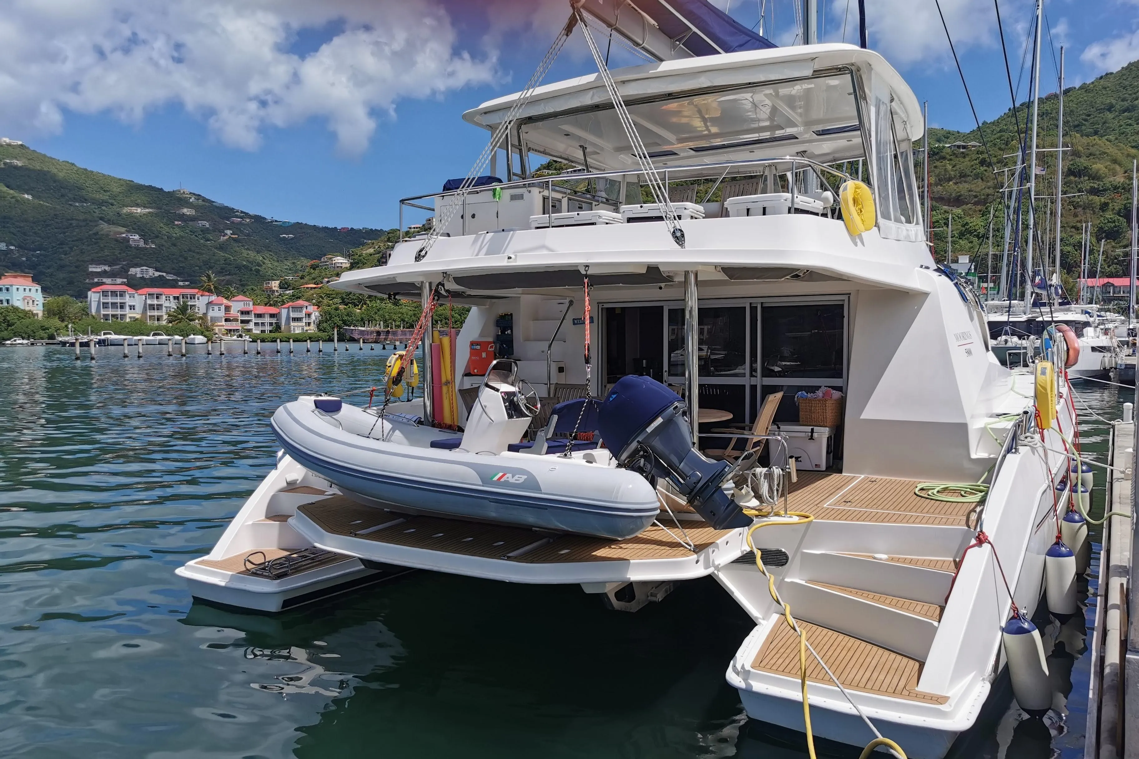 Luxury Leopard 58 yacht docked with inflatable boat, scenic marina backdrop.