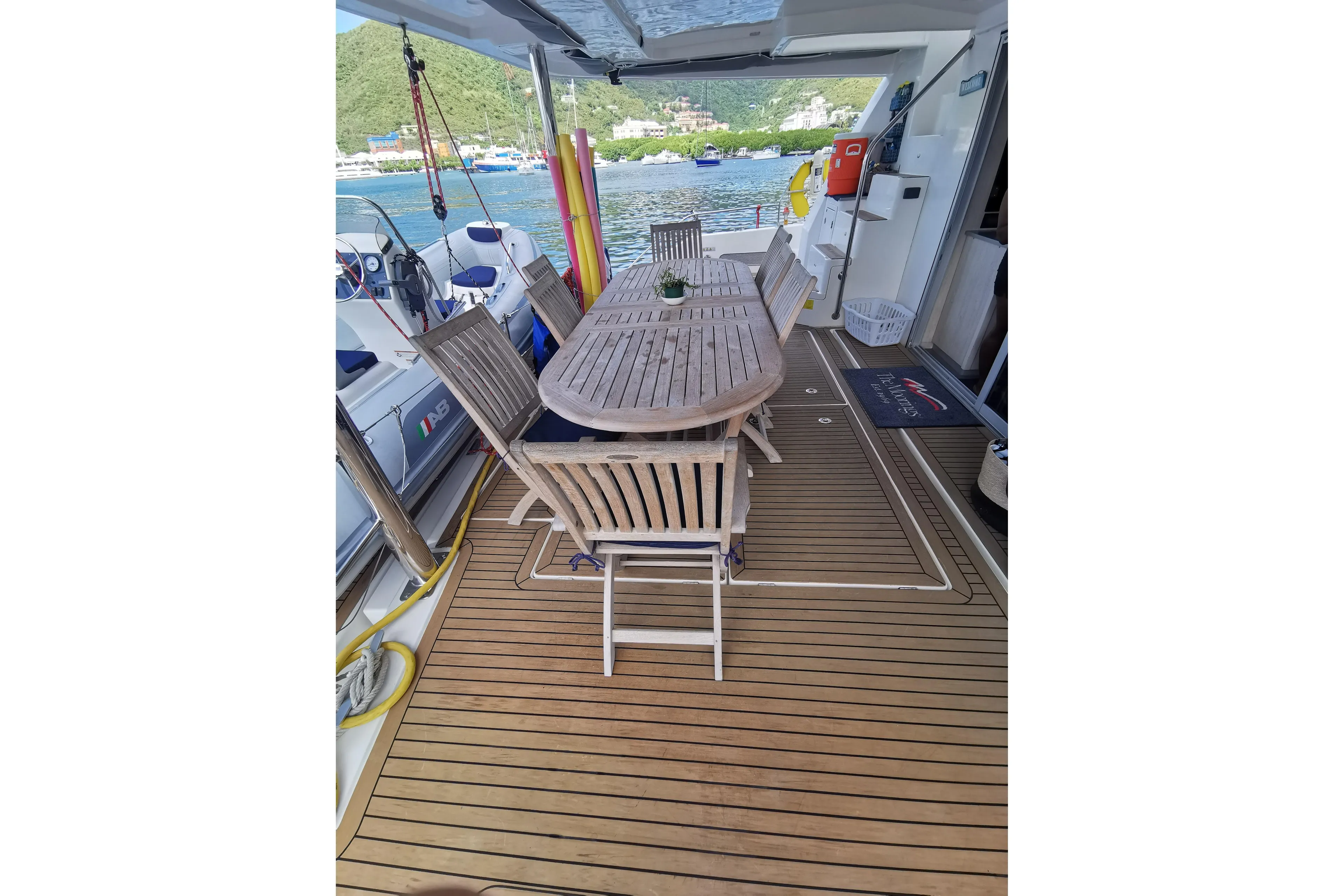 Luxurious Leopard 58 yacht deck with wooden dining table, chairs, and scenic waterfront view.