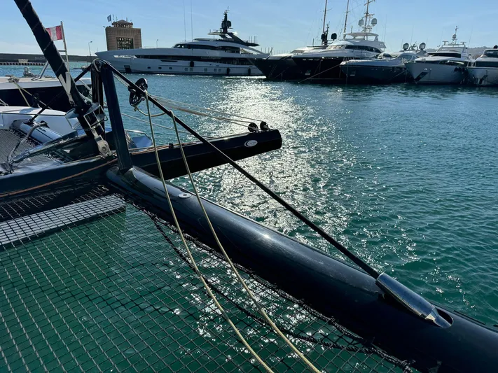  Yacht Photos Pics 2023 Outremer 55 catamaran docked in a marina with luxury yachts in the background.