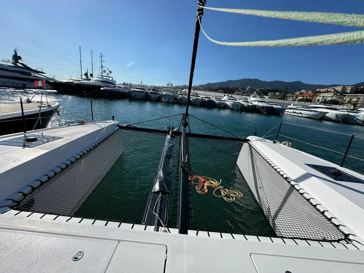  Yacht Photos Pics 2023 Outremer 55 catamaran docked in a marina with yachts and mountains in the background.