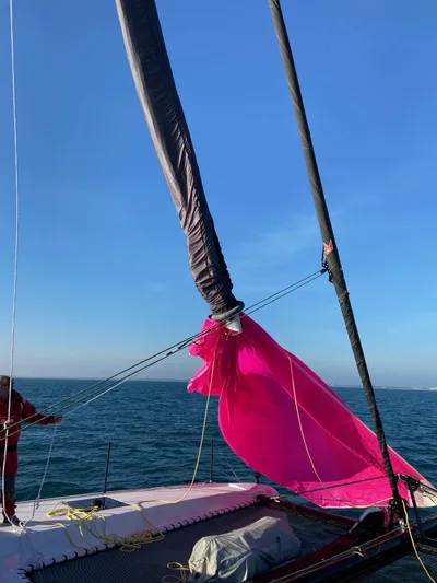  Yacht Photos Pics 2023 Outremer 55 sailboat with vibrant pink sail against clear blue sky.