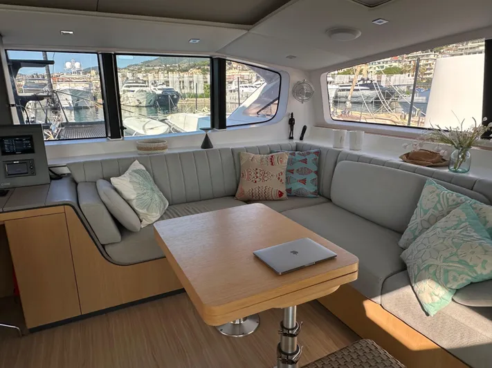  Yacht Photos Pics Modern interior of 2023 Outremer 55 yacht with cozy seating and scenic marina view.