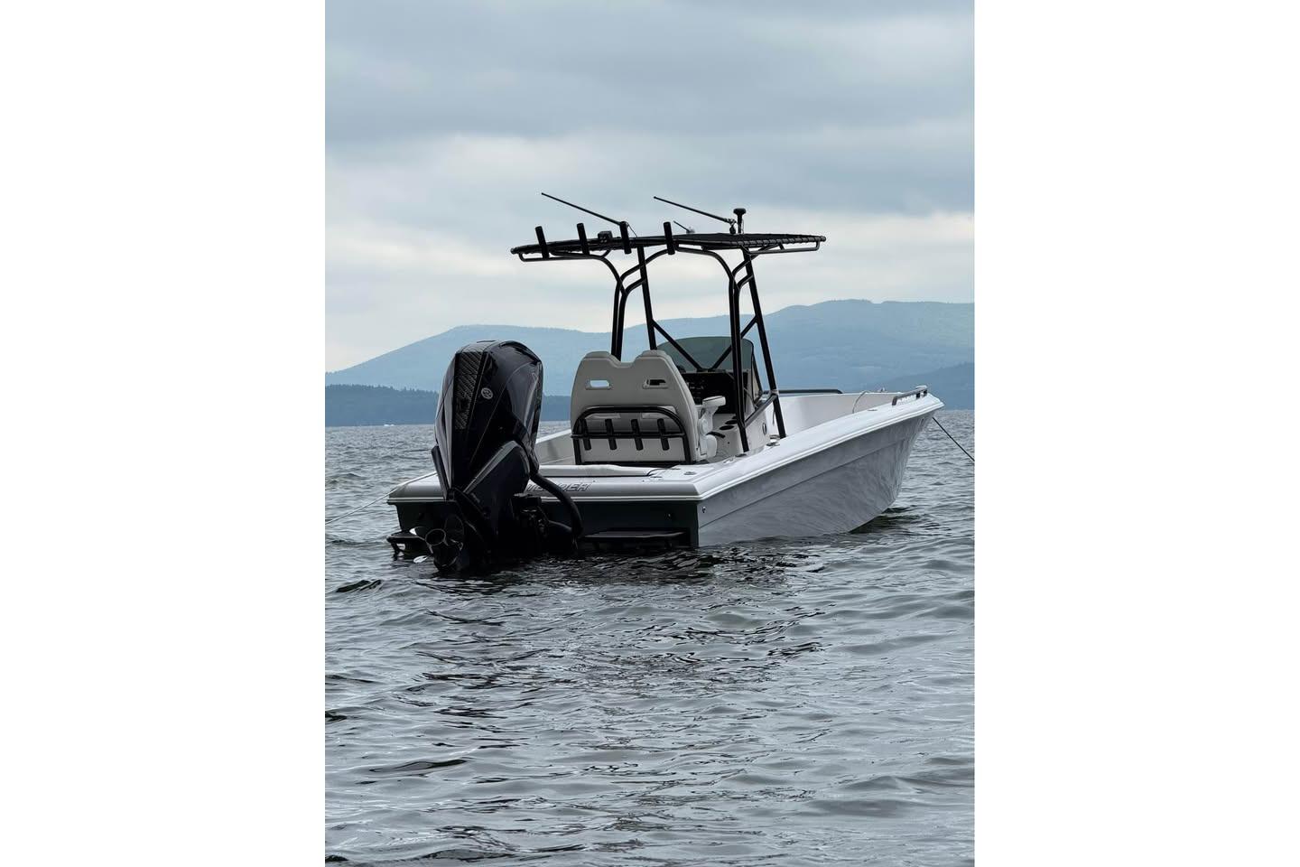 Concept 27 boat from 2004 on a calm lake with mountainous background.