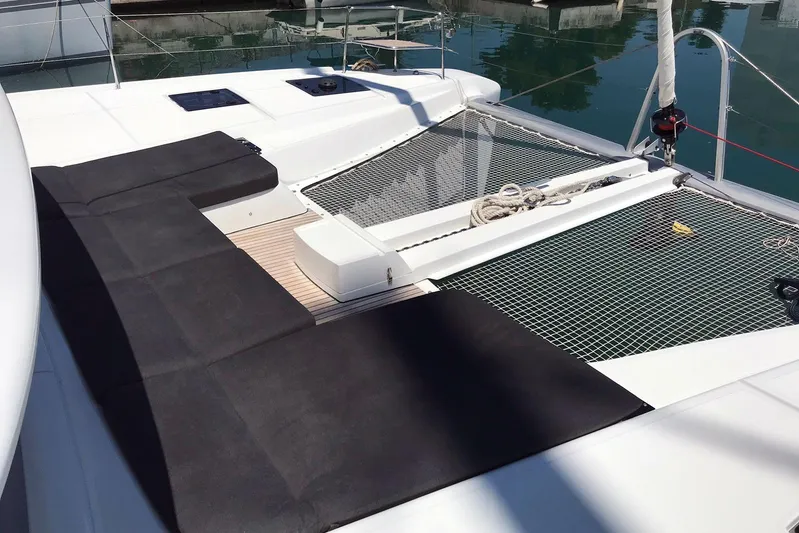  Yacht Photos Pics 2019 Lagoon 50 catamaran deck with black cushions and netting, docked in marina.