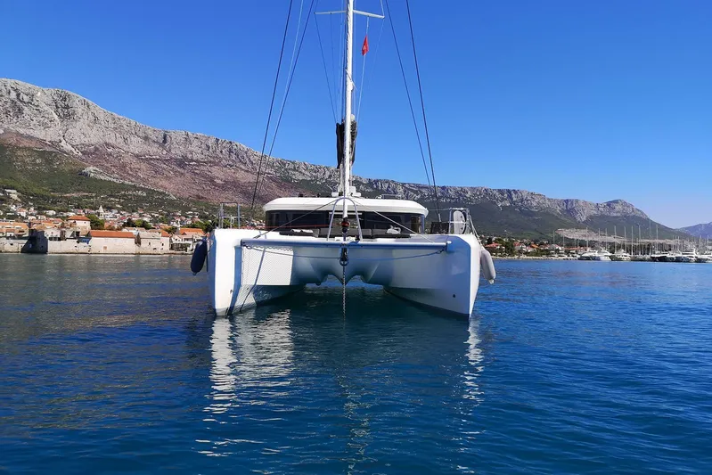  Yacht Photos Pics 2019 Lagoon 50 catamaran on calm water with mountainous backdrop.