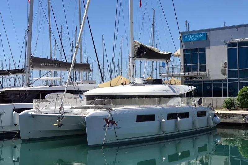  Yacht Photos Pics 2019 Lagoon 50 catamaran docked near a restaurant and reception area.