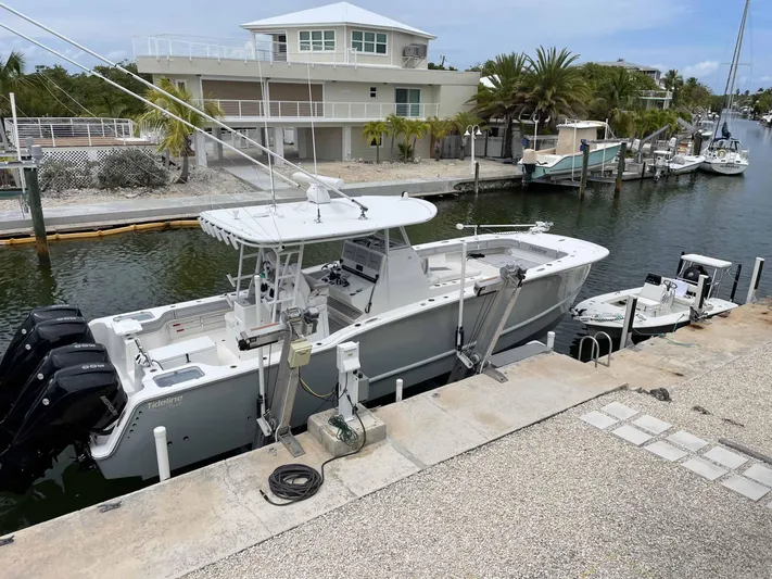  Yacht Photos Pics 2020 Tideline 365 boat docked by waterfront homes, featuring triple outboard engines.