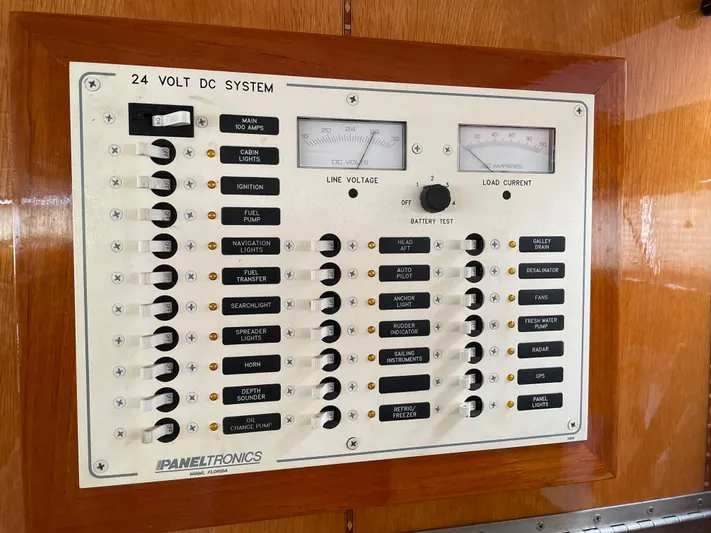  Yacht Photos Pics 1974 custom center cockpit 24V DC system panel with switches and gauges on wooden background.