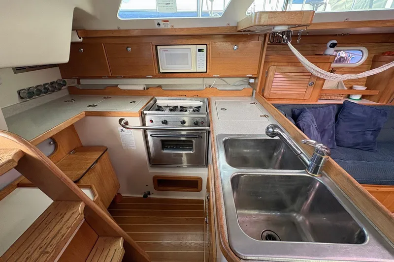 Kindred Spirit Yacht Photos Pics 2005 Catalina 36 MkII yacht interior kitchen with stove, sink, and wooden cabinetry.