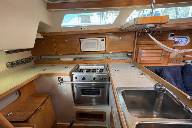 Kindred Spirit Yacht Photos Pics 2005 Catalina 36 MkII yacht kitchen with stove, microwave, and wooden cabinetry.