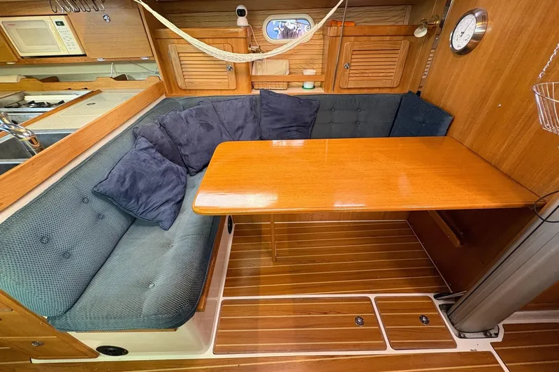 Kindred Spirit Yacht Photos Pics Cozy dining area in 2005 Catalina 36 MkII sailboat with wooden table and cushioned seating.