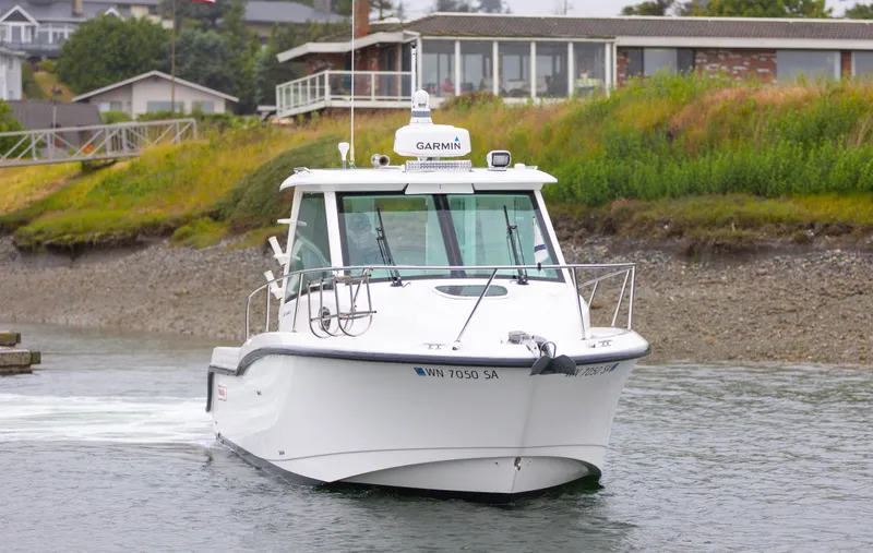Boston Whaler 285 Yacht Photos Pics 2013 Boston Whaler 285 Conquest Pilothouse boat on water near shoreline.