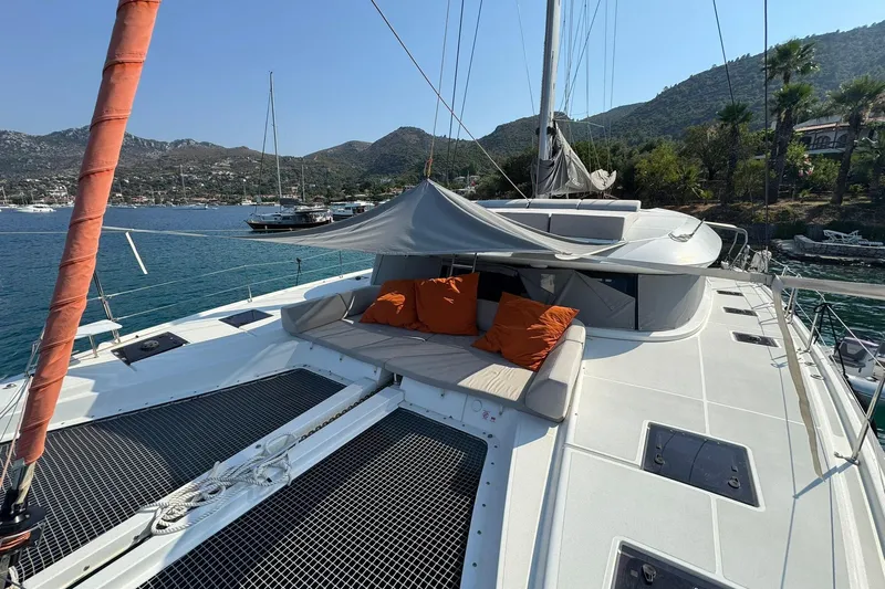  Yacht Photos Pics Luxurious 2021 Excess 15 catamaran with sunshade and cushions, docked in scenic coastal waters.