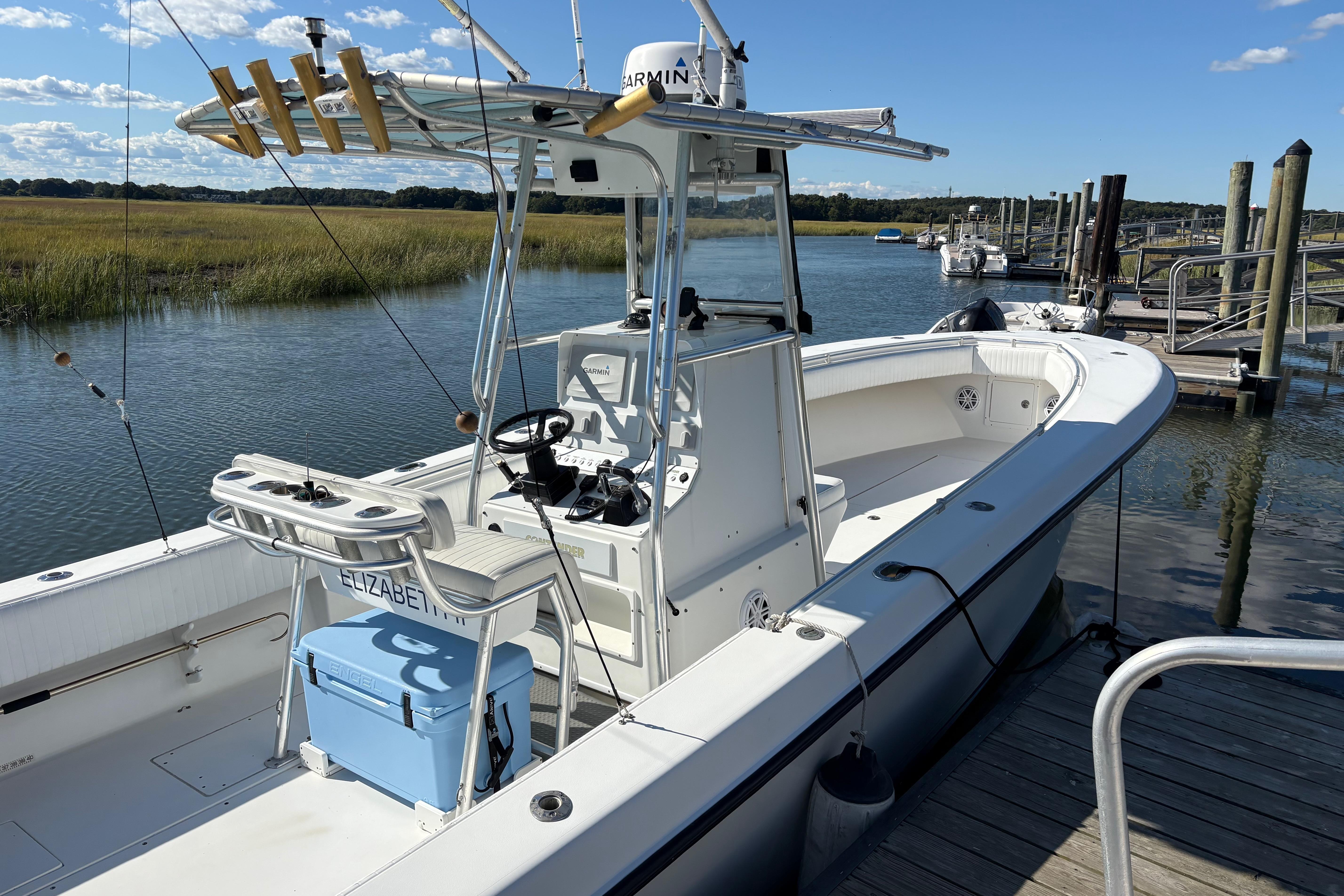 2001 Contender 31 Open boat docked by a scenic river with fishing gear.