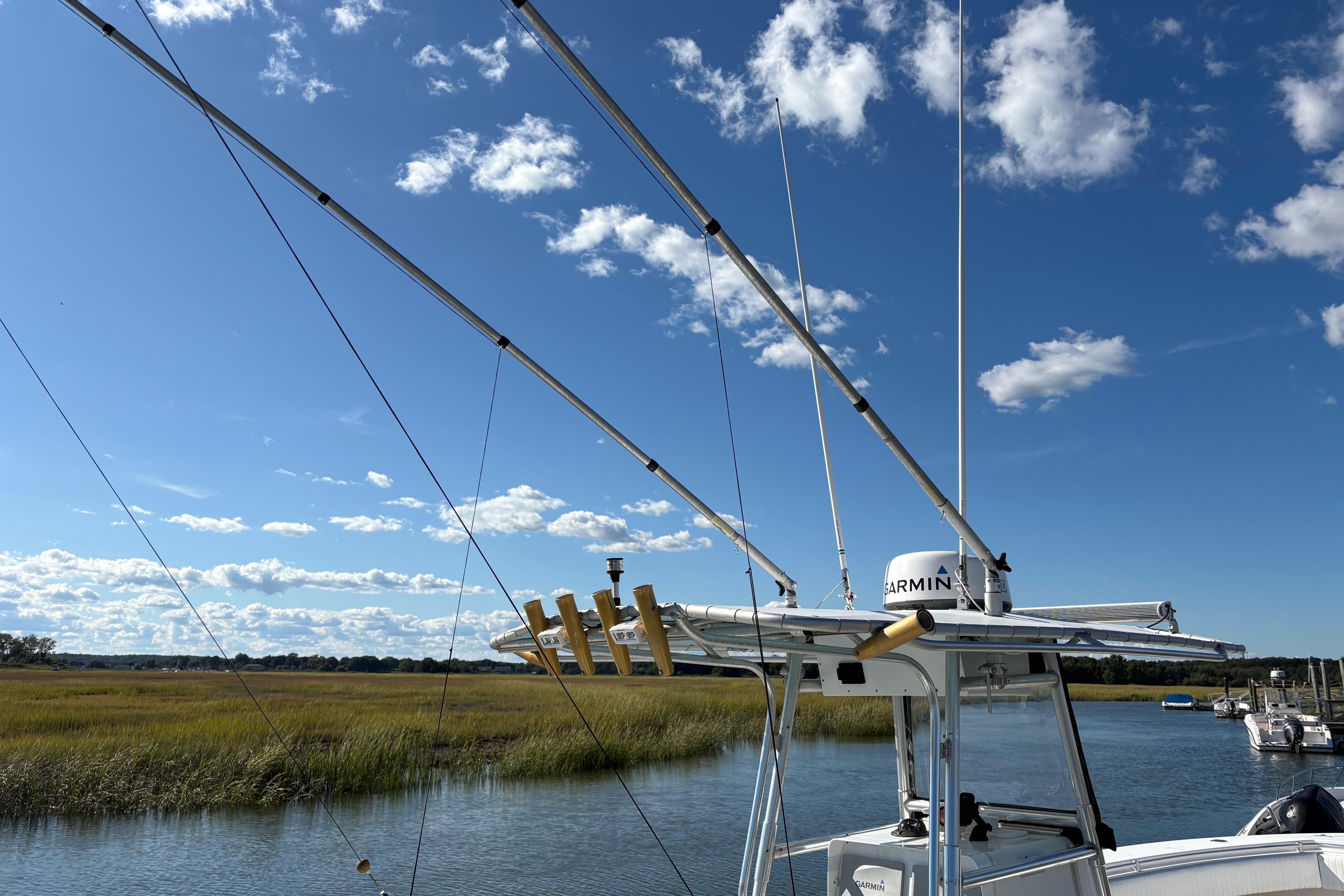 2001 Contender 31 Open boat with fishing rods, clear sky, and marshland background.