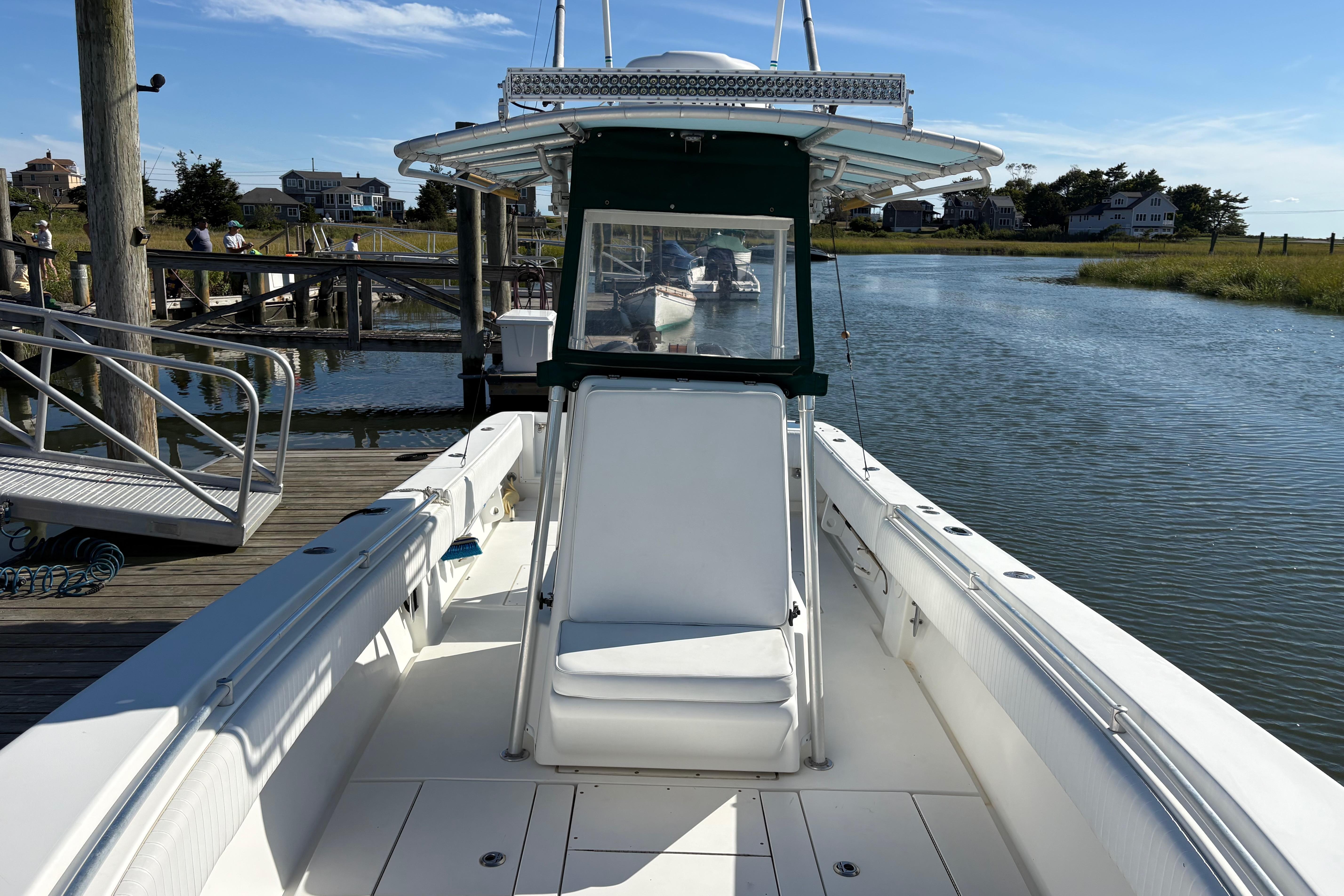 2001 Contender 31 Open boat docked by a serene waterfront on a sunny day.