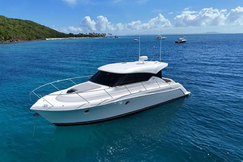  Yacht Photos Pics 2022 Tiara Yachts C39 Coupe on clear blue water near a lush green island.