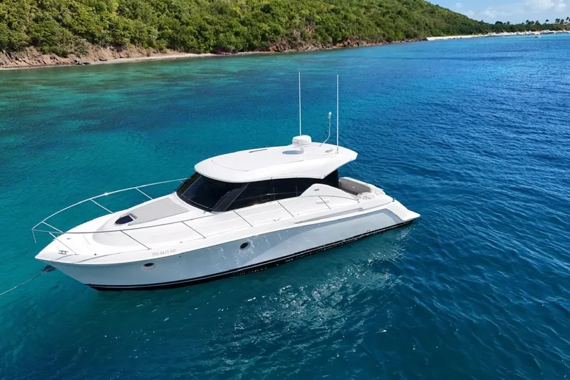  Yacht Photos Pics 2022 Tiara Yachts C39 Coupe cruising in clear blue waters near a lush coastline.