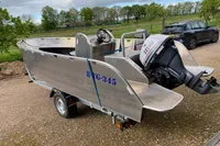 Aluminum boat on trailer with outboard motor, Evens Defender 2022 model, parked outdoors.