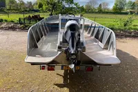 Aluminum boat with outboard motor, Evens Defender 2022, parked outdoors on a sunny day.