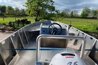 2022 Evens Defender boat with steering wheel, parked outdoors near green fields and trees.