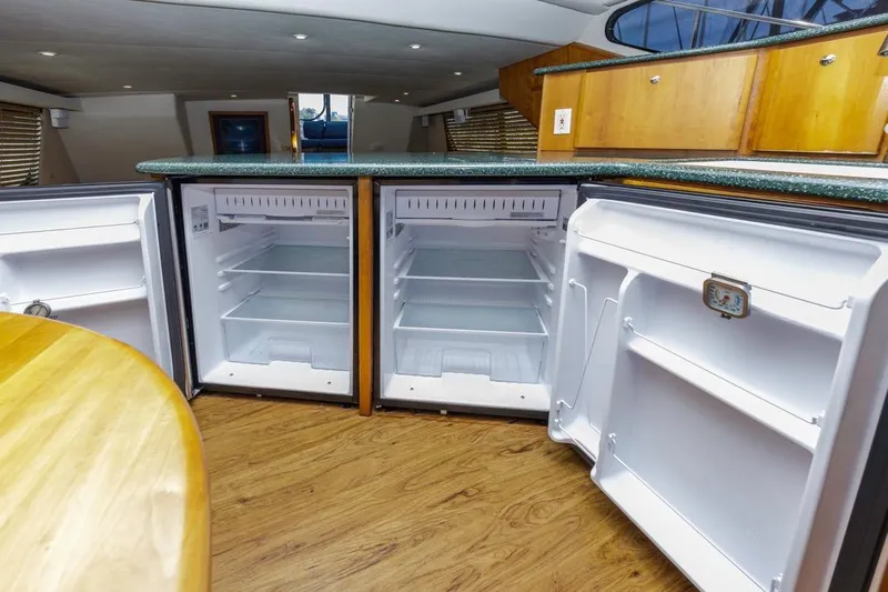 Just Joyce Yacht Photos Pics Interior of a 2000 Silverton 435 yacht featuring open refrigerators and wooden cabinetry.