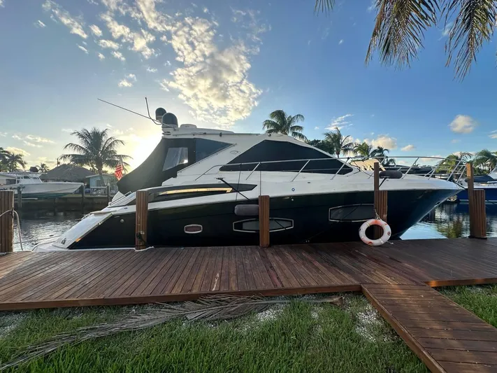 Day Off Yacht Photos Pics 2015 Regal 53 Sport Coupe yacht docked, surrounded by palm trees and a sunny sky.