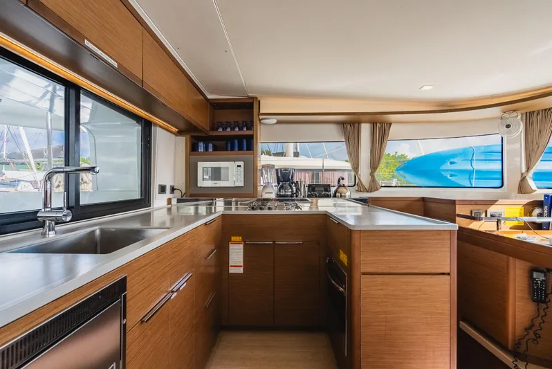 As You Wish Yacht Photos Pics Modern kitchen interior of 2020 Lagoon 46 catamaran with wood cabinetry and stainless steel appliances.