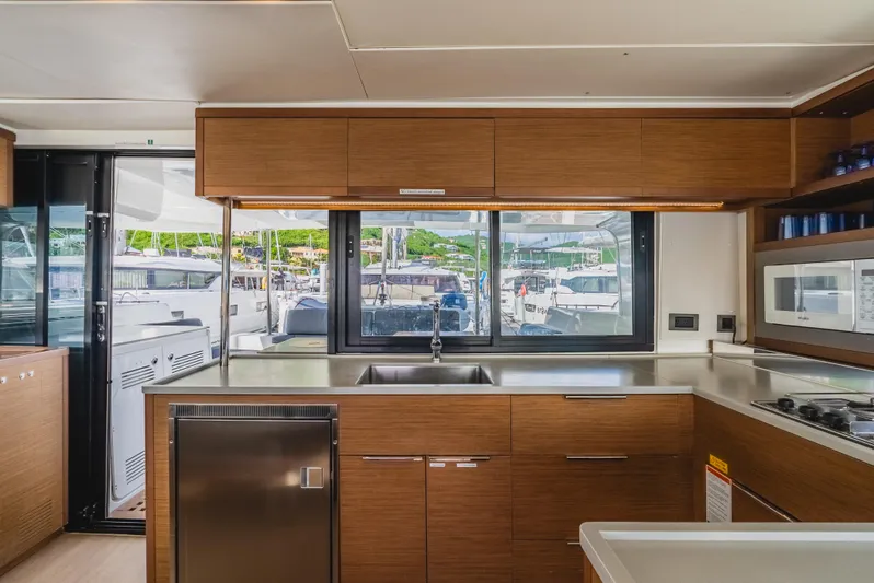 As You Wish Yacht Photos Pics Modern kitchen interior of 2020 Lagoon 46 yacht with wood cabinetry and large windows.