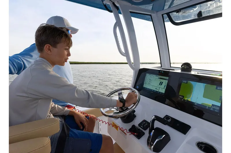  Yacht Photos Pics Manufacturer Provided Image: Young person steering 2025 Sportsman Masters 267 Bay Boat on open water.