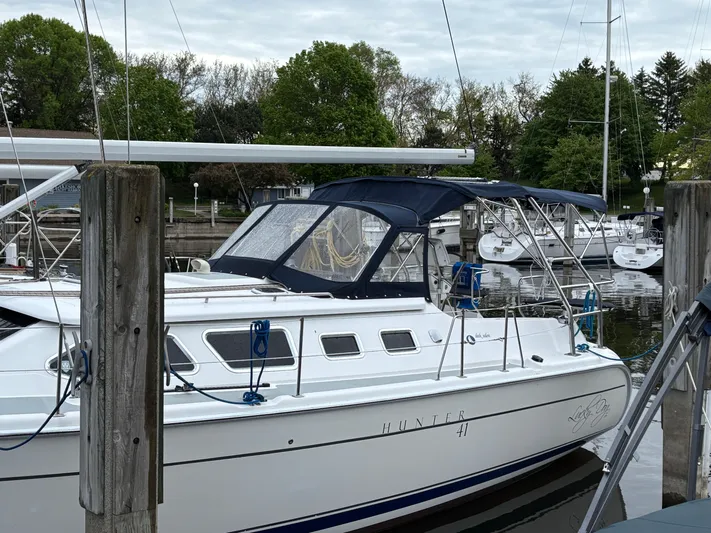 Lucky Dog Too Yacht Photos Pics 2008 Hunter 41 DS sailboat docked at marina, surrounded by trees and other boats.