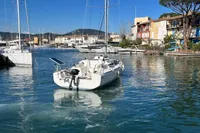 Sailboat Maree Haute DJANGO 770, 2011, docked in a scenic marina with colorful buildings.