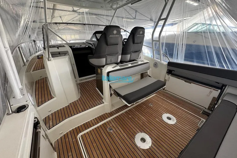 Gigage Yacht Photos Pics 2020 Jeanneau Cap Camarat 9.0 WA boat interior with sleek seating and wood flooring.