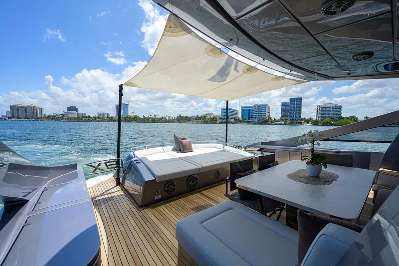 Shine Yacht Photos Pics Luxurious 2022 Pershing 9X yacht deck with seating, table, and waterfront view.