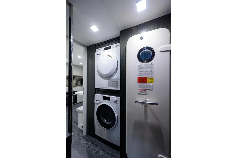 Shine Yacht Photos Pics Laundry area inside 2022 Pershing 9X yacht, featuring modern washer and dryer units.