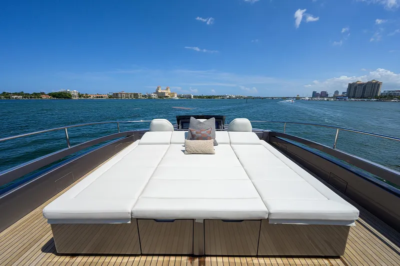 Shine Yacht Photos Pics Luxurious 2022 Pershing 9X yacht with spacious sunbed on deck, cruising in clear blue waters.