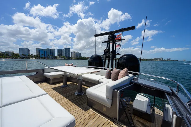 Shine Yacht Photos Pics Luxurious 2022 Pershing 9X yacht deck with modern seating, ocean view, and city skyline.