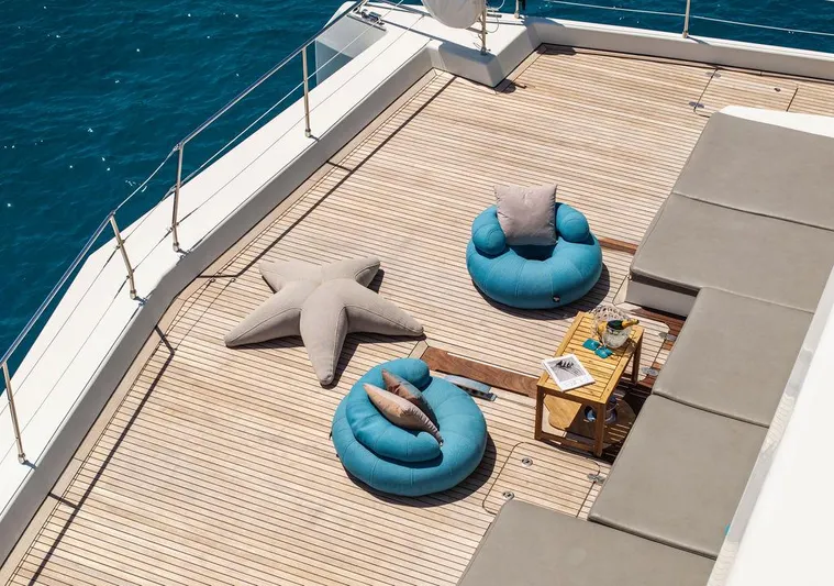 Rosa Del Mar Yacht Photos Pics Luxurious Sunreef Supreme 68 yacht deck with plush seating, star-shaped cushion, and ocean view.