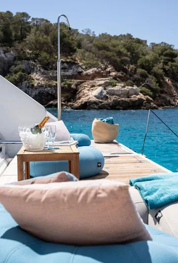 Rosa Del Mar Yacht Photos Pics Luxurious Sunreef Supreme 68 yacht deck with plush seating, overlooking turquoise waters and rocky coastline.