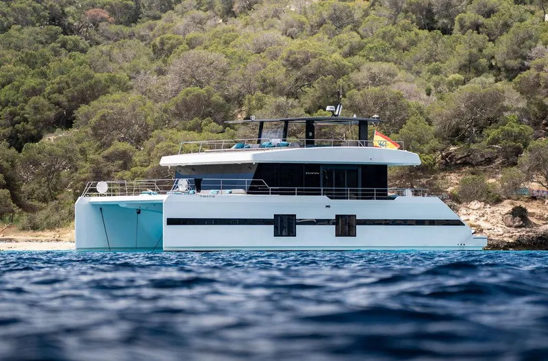 Rosa Del Mar Yacht Photos Pics Sunreef Supreme 68 yacht, 2017 model, anchored near a lush, forested coastline.