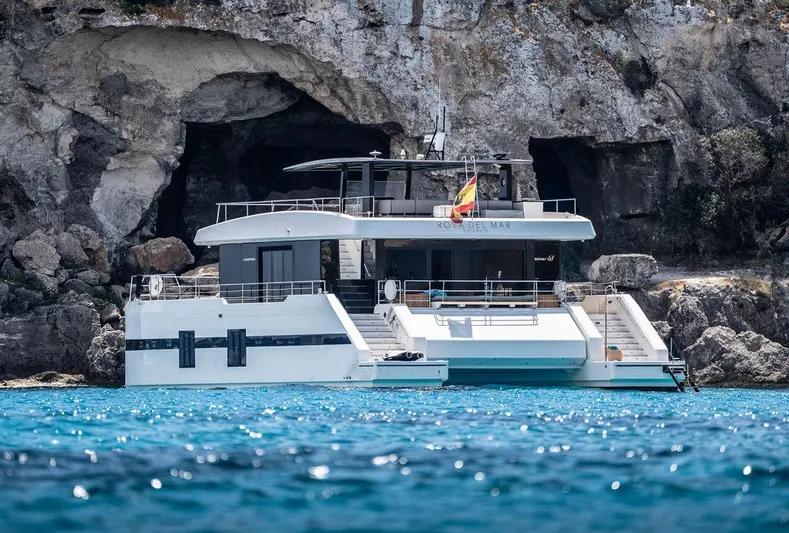 Rosa Del Mar Yacht Photos Pics Luxurious 2017 Sunreef Supreme 68 yacht anchored near rocky cliffs and clear blue water.
