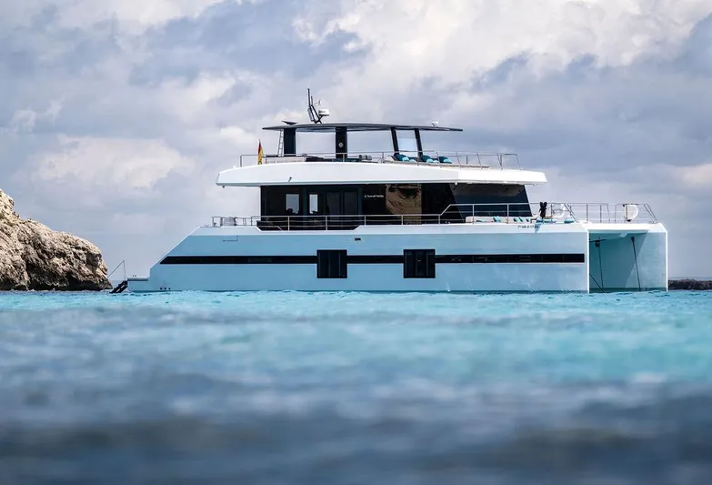 Rosa Del Mar Yacht Photos Pics Sunreef Supreme 68 yacht, 2017 model, cruising on clear blue waters under a cloudy sky.