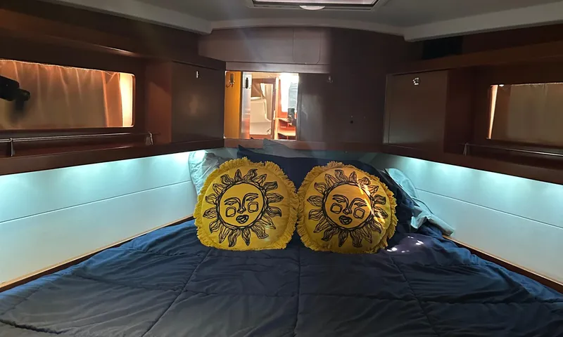 Lele Kalua Yacht Photos Pics Interior cabin of 2014 Beneteau Oceanis 41 with sun-themed pillows on a bed.