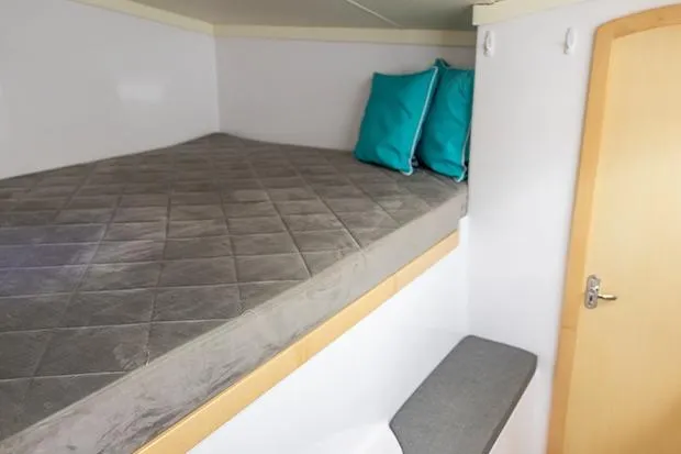 Honu Kai Yacht Photos Pics Cozy cabin interior of 2019 Seawind 1260 with bed and teal pillows.