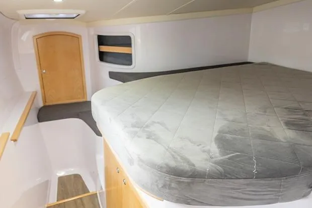 Honu Kai Yacht Photos Pics 2019 Seawind 1260 interior cabin with bed, wooden door, and modern design.