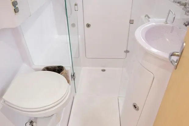 Honu Kai Yacht Photos Pics 2019 Seawind 1260 yacht bathroom with toilet, sink, and shower in compact layout.