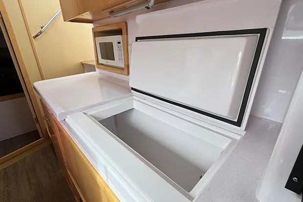 Honu Kai Yacht Photos Pics 2019 Seawind 1260 yacht kitchen with open fridge and microwave.