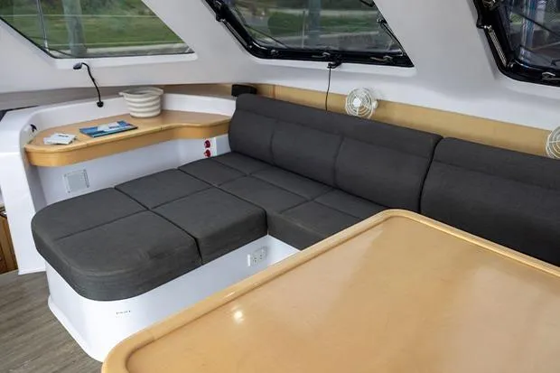Honu Kai Yacht Photos Pics 2019 Seawind 1260 interior with gray seating and wooden table in a modern yacht cabin.