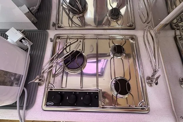 Honu Kai Yacht Photos Pics Stainless steel stove on 2019 Seawind 1260 catamaran, featuring three burners and control knobs.